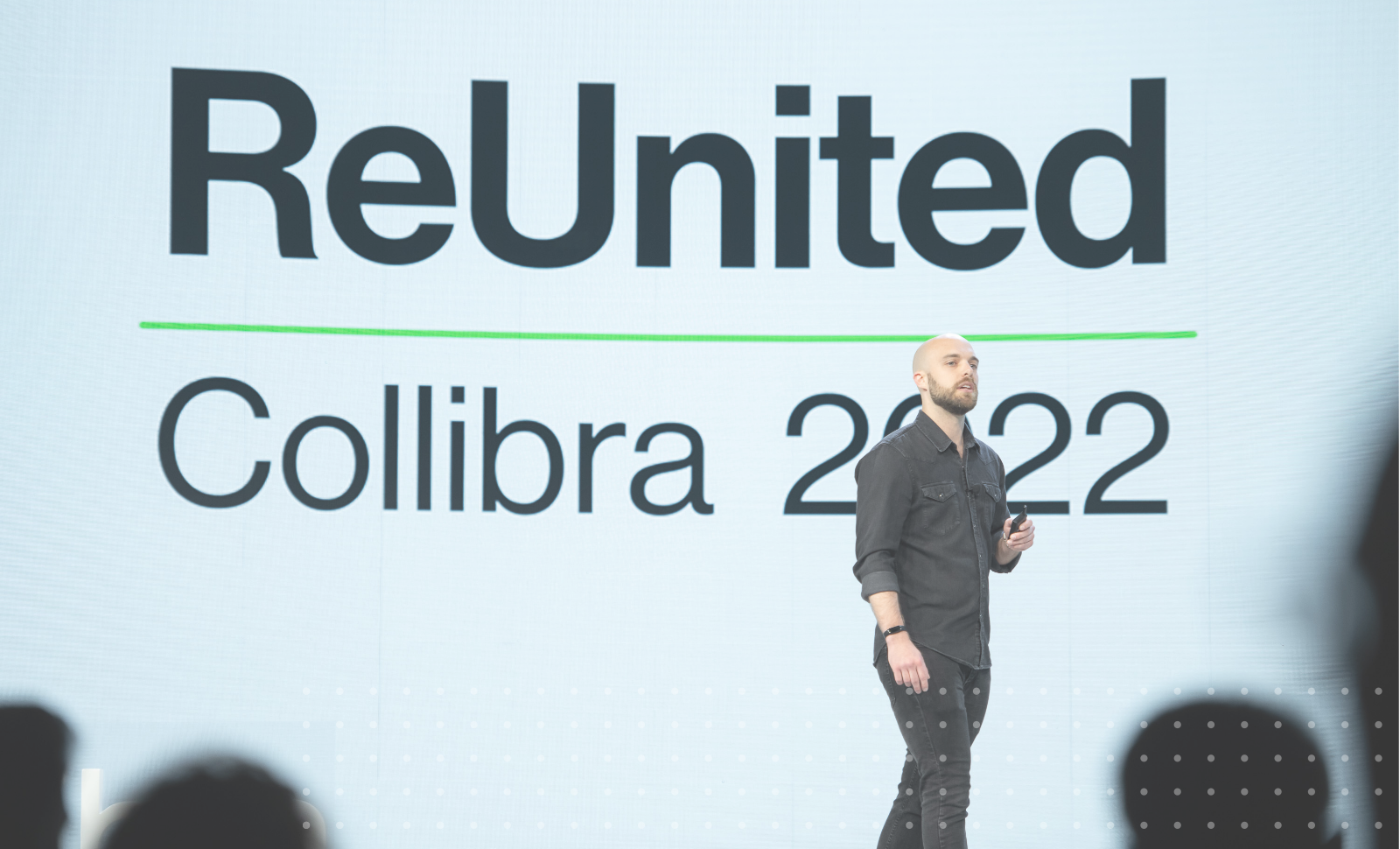 科迪·施洛特在舞台上展示了一个屏幕，上面写着“团聚的Collibra 2022”亚愽视频